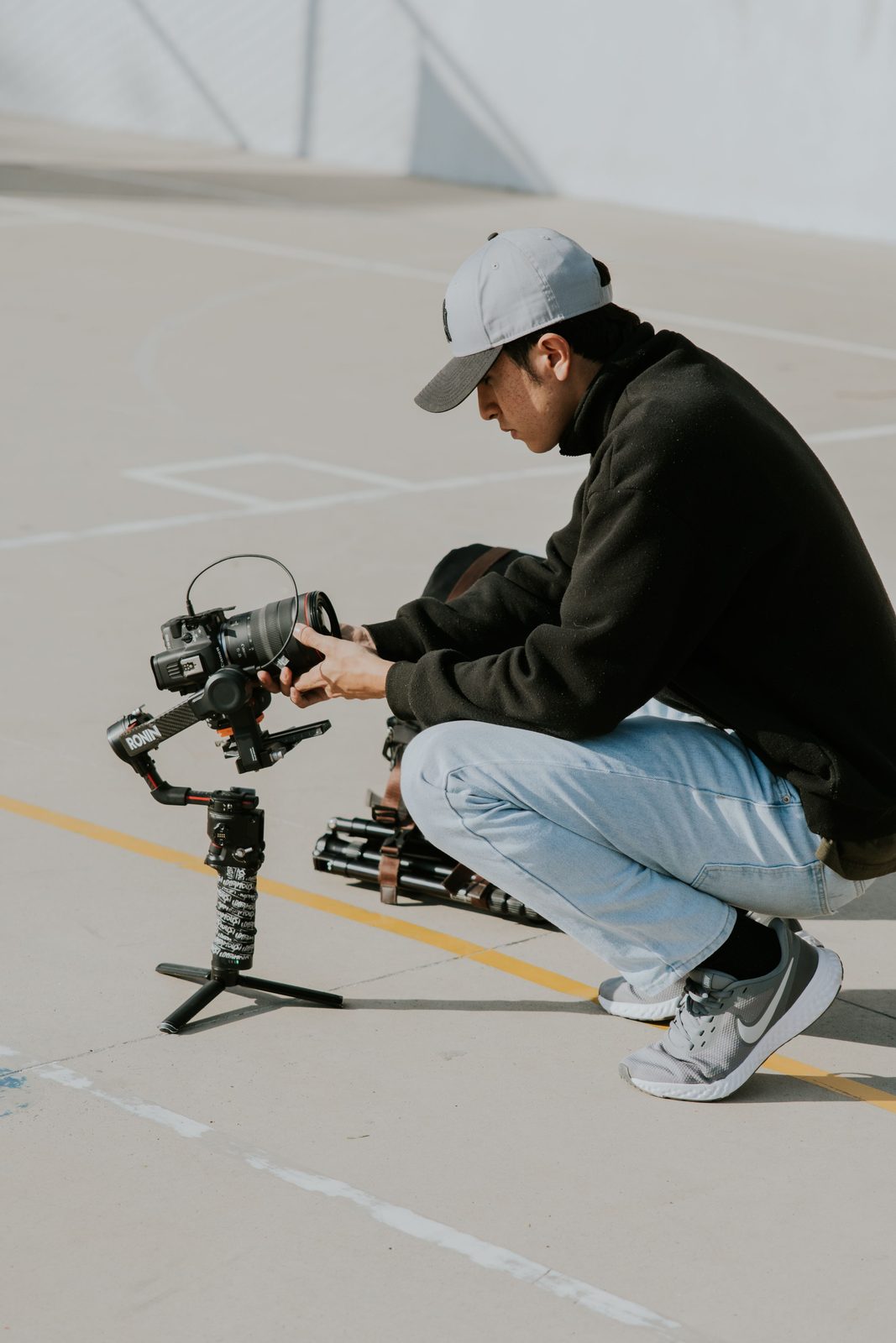 Illustrative stock photograph of a person crouching to set up a camera on a gimbal